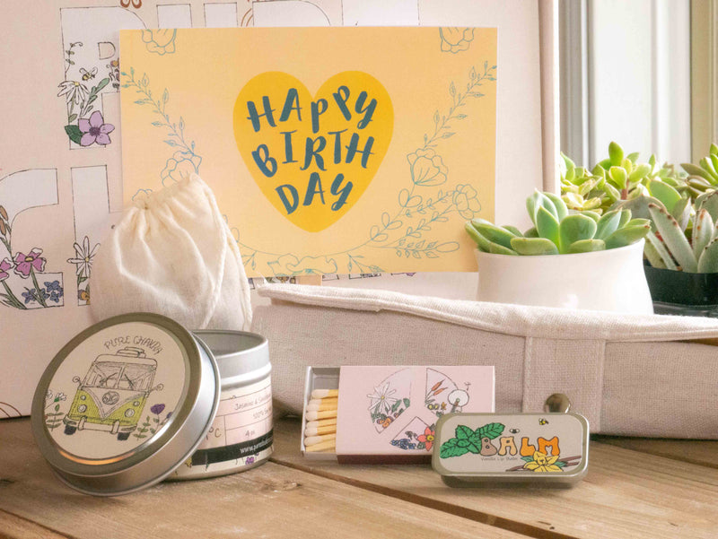 Happy Birthday Succulent Gift Box with bamboo cutlery set, candle, custom matches, lavender sachet and lip balm, in front of a decorative gift box