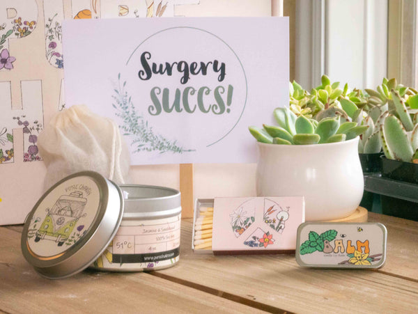 Surgery Succs Succulent Gift Box with candle, custom matches, lavender sachet and lip balm, in front of a decorative gift box