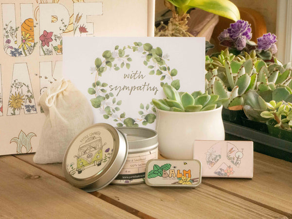 With Sympathy Succulent Gift Box with candle, custom matches, lavender sachet and lip balm, in front of a decorative gift box