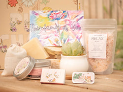 Thinking of you Succulent Gift Box with relax bath salt, natural soap, candle, custom matches, lavender sachet and lip balm, in front of a decorative gift box