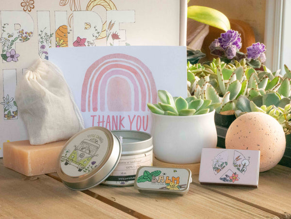 Thank You Succulent Gift Box with natural soap, bath bomb, candle, custom matches, lavender sachet and lip balm, in front of a decorative gift box