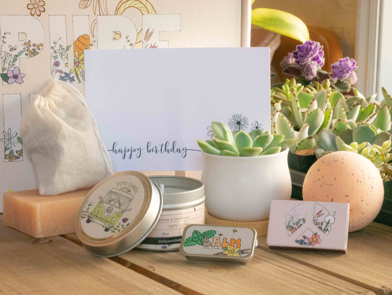 Happy Birthday Succulent Gift Box with natural soap, bath bomb, candle, custom matches, lavender sachet and lip balm, in front of a decorative gift box
