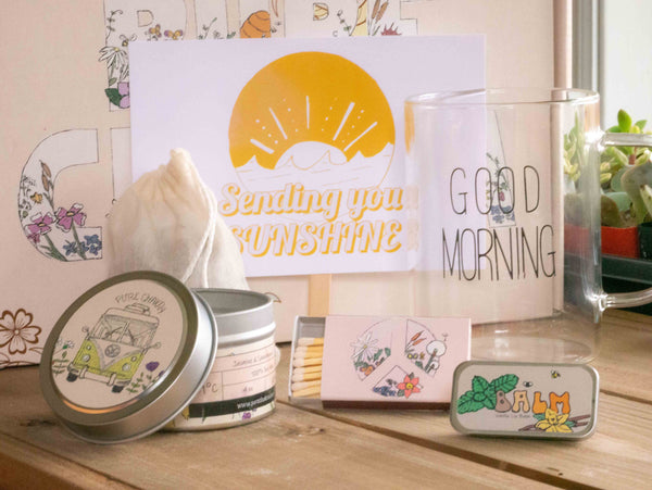 Sending you sunshine Gift Box with Good Morning Mug, candle, custom matches, lavender sachet and lip balm, in front of a decorative gift box