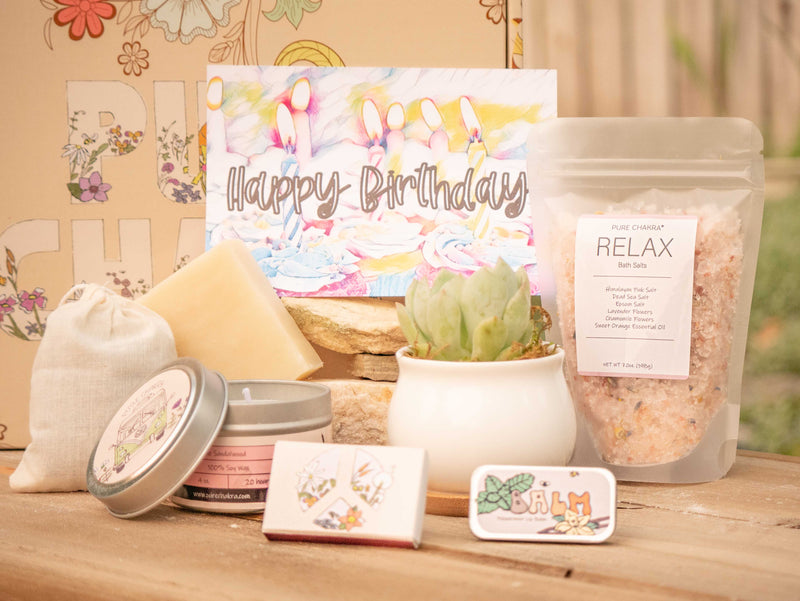 Happy Birthday Succulent Gift Box with relax bath salt, natural soap, candle, custom matches, lavender sachet and lip balm, in front of a decorative gift box