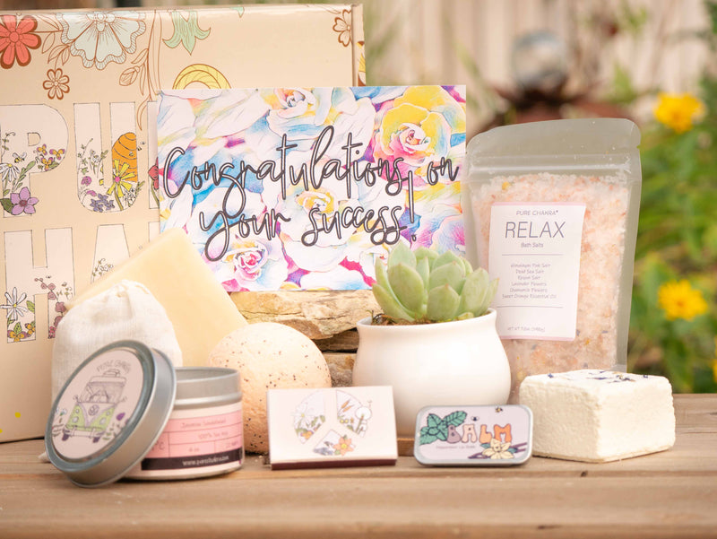 Congratulations on your success Succulent Gift Box with relax bath salt, natural soap, bath bomb, shower steamer, candle, custom matches, lavender sachet and lip balm, in front of a decorative gift box