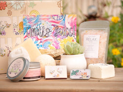 Finals Succ! Succulent Gift Box with relax bath salt, natural soap, bath bomb, shower steamer, candle, custom matches, lavender satchet and lip balm, in front of a decorative gift box