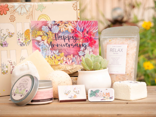 Happy Anniversary Succulent Gift Box with relax bath salt, natural soap, bath bomb, shower steamer, candle, custom matches, lavender satchet and lip balm, in front of a decorative gift box