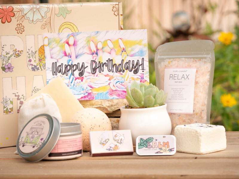 Happy Birthday Succulent Gift Box with relax bath salt, natural soap, bath bomb, shower steamer, candle, custom matches, lavender sachet and lip balm, in front of a decorative gift box