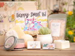 Happy Sweet 16 Succulent Gift Box with relax bath salt, natural soap, bath bomb, shower steamer, candle, custom matches, lavender sachet and lip balm, in front of a decorative gift box