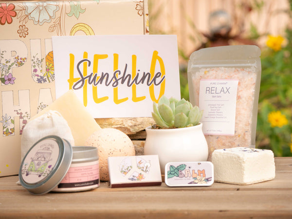 Hello Sunshine Succulent Gift Box with relax bath salt, natural soap, bath bomb, shower steamer, candle, custom matches, lavender satchet and lip balm, in front of a decorative gift box