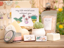 My life would succ without you Succulent Gift Box with relax bath salt, natural soap, bath bomb, shower steamer, candle, custom matches, lavender satchet and lip balm, in front of a decorative gift box