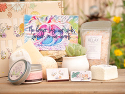 No longer by our side, forever in our hearts Succulent Gift Box with relax bath salt, natural soap, bath bomb, shower steamer, candle, custom matches, lavender sachet and lip balm, in front of a decorative gift box