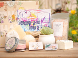 Sending you love and hugs Succulent Gift Box with relax bath salt, natural soap, bath bomb, shower steamer, candle, custom matches, lavender satchet and lip balm, in front of a decorative gift box