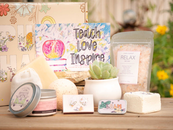Teach Love Inspire Succulent Gift Box with relax bath salt, natural soap, bath bomb, shower steamer, candle, custom matches, lavender sachet and lip balm, in front of a decorative gift box